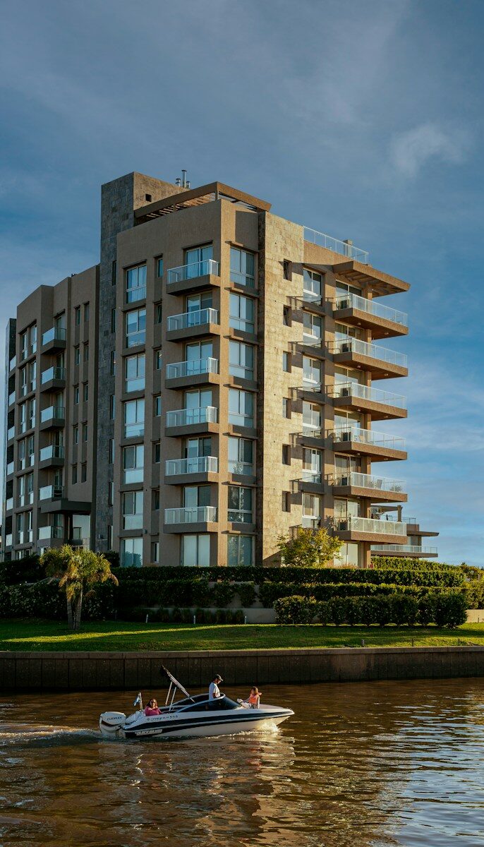 a boat traveling down a river next to a tall building